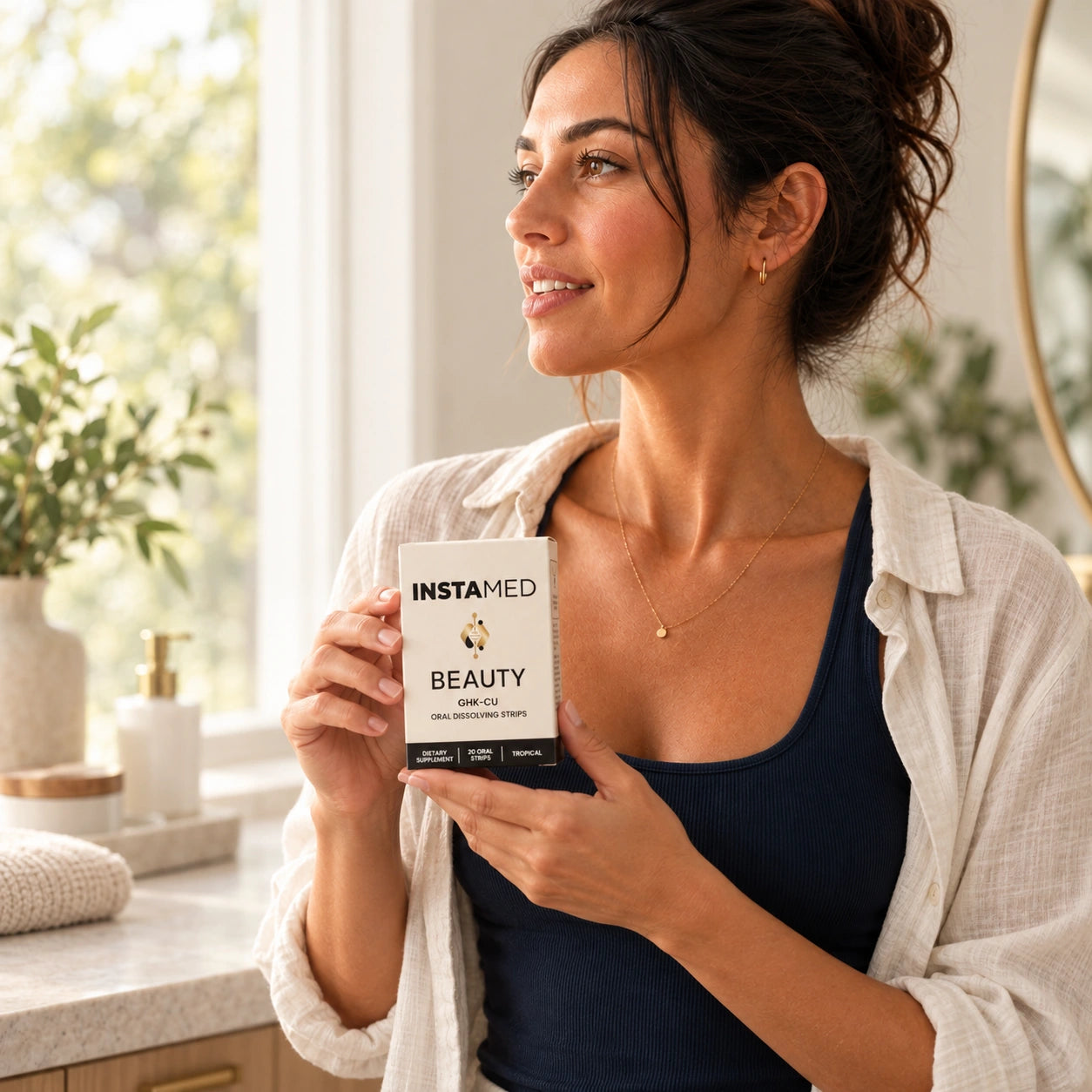 Empowerd Edge model holding the InstaMed Beauty GHK-Cu box in a sunlit setting.